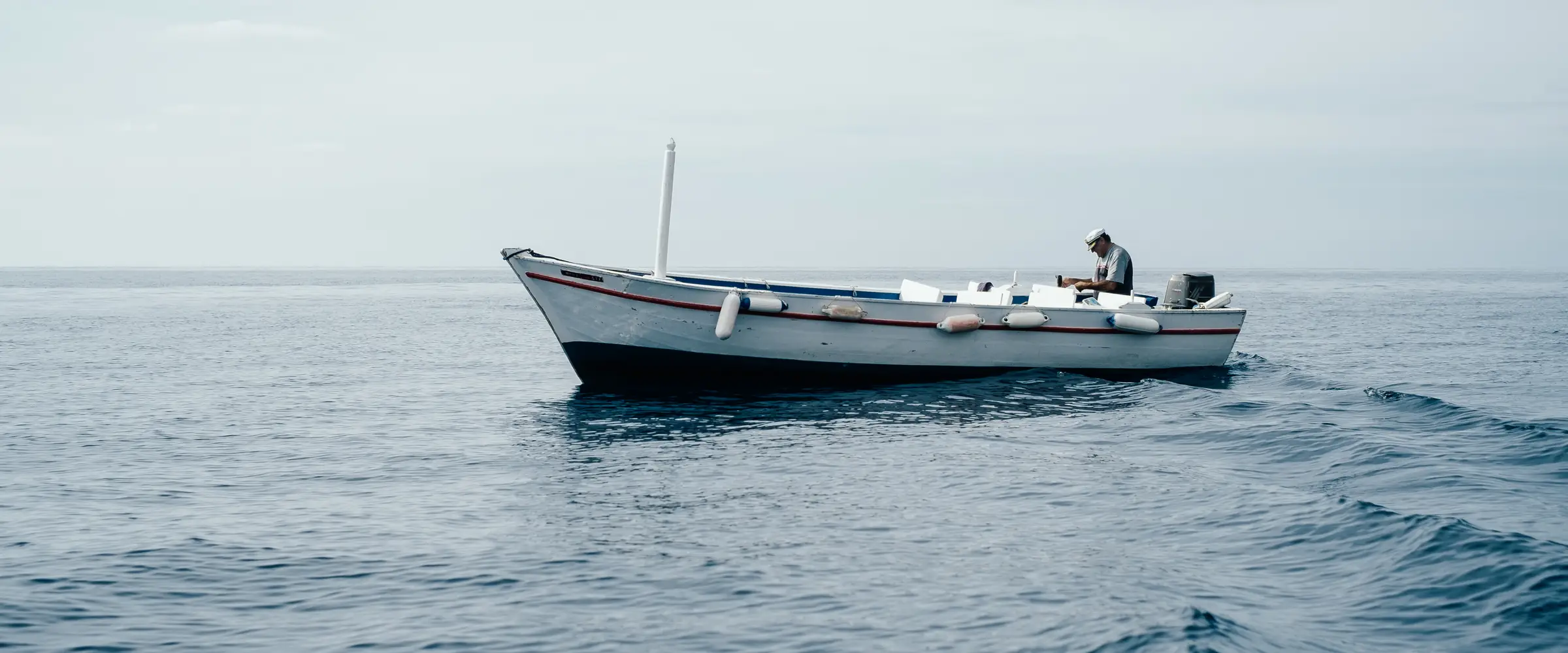 Côte rocheuse et crique turquoise, un bateau au mouillage